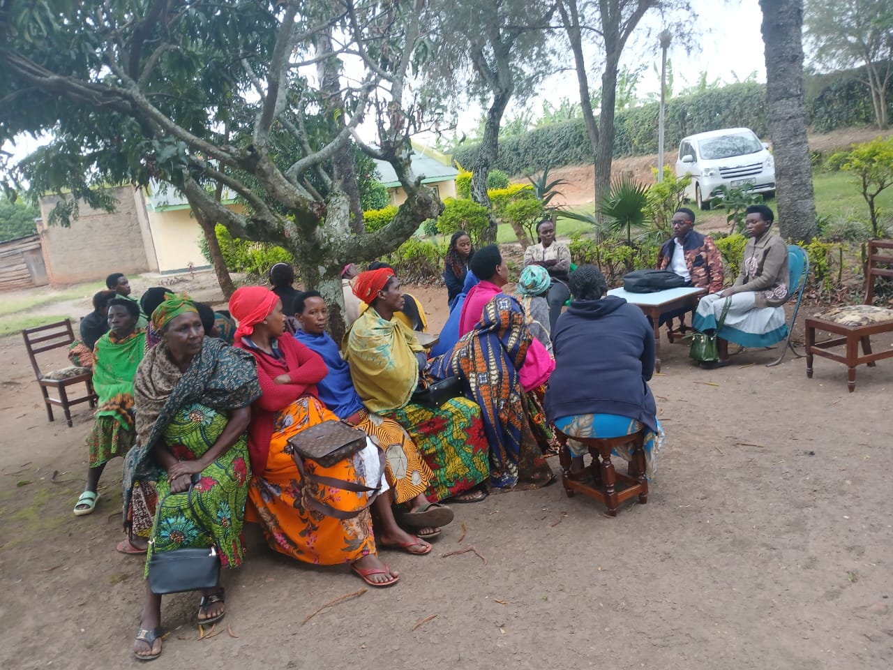 Women group meeting with field officers under trees